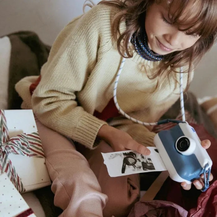 Criança sorridente a usar a KidyWolf Máquina Fotográfica Digital, que imprime uma foto a preto e branco instantaneamente.