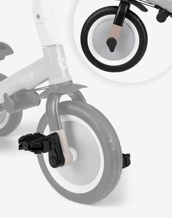 Detalhe em close-up dos pedais pretos e das rodas em borracha EVA do triciclo Kikkaboo FLIP, com círculo de aumento focado no eixo da roda dianteira.