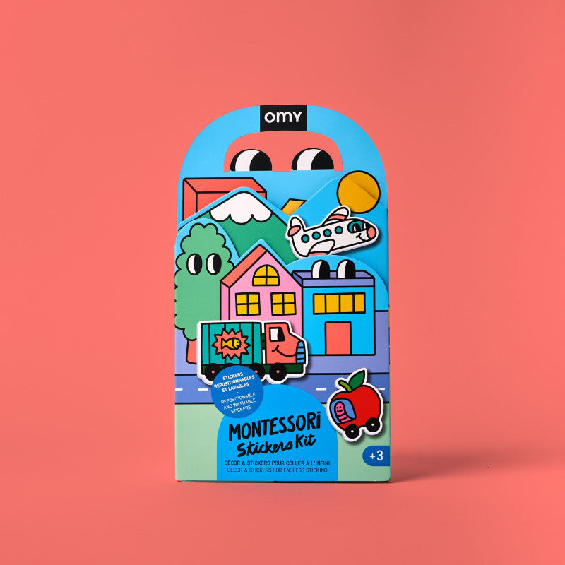 Embalagem em arco azul e verde do Kit de Autocolantes Montessori OMY, exibindo ilustrações coloridas de casas, árvores, um camião e um avião.