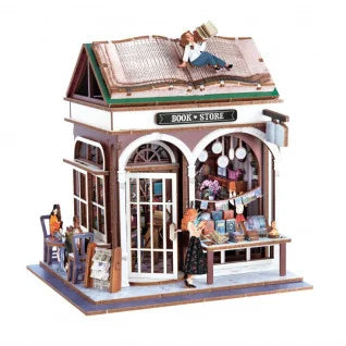 Vista detalhada do diorama da livraria montado, com figuras, mesas e a figura de um leitor no telhado em forma de livro.
