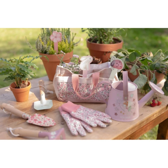 Conjunto de jardinagem Little Dutch Fairy Garden em uso sobre uma mesa de madeira ao ar livre, rodeado por vasos de plantas e vegetação.