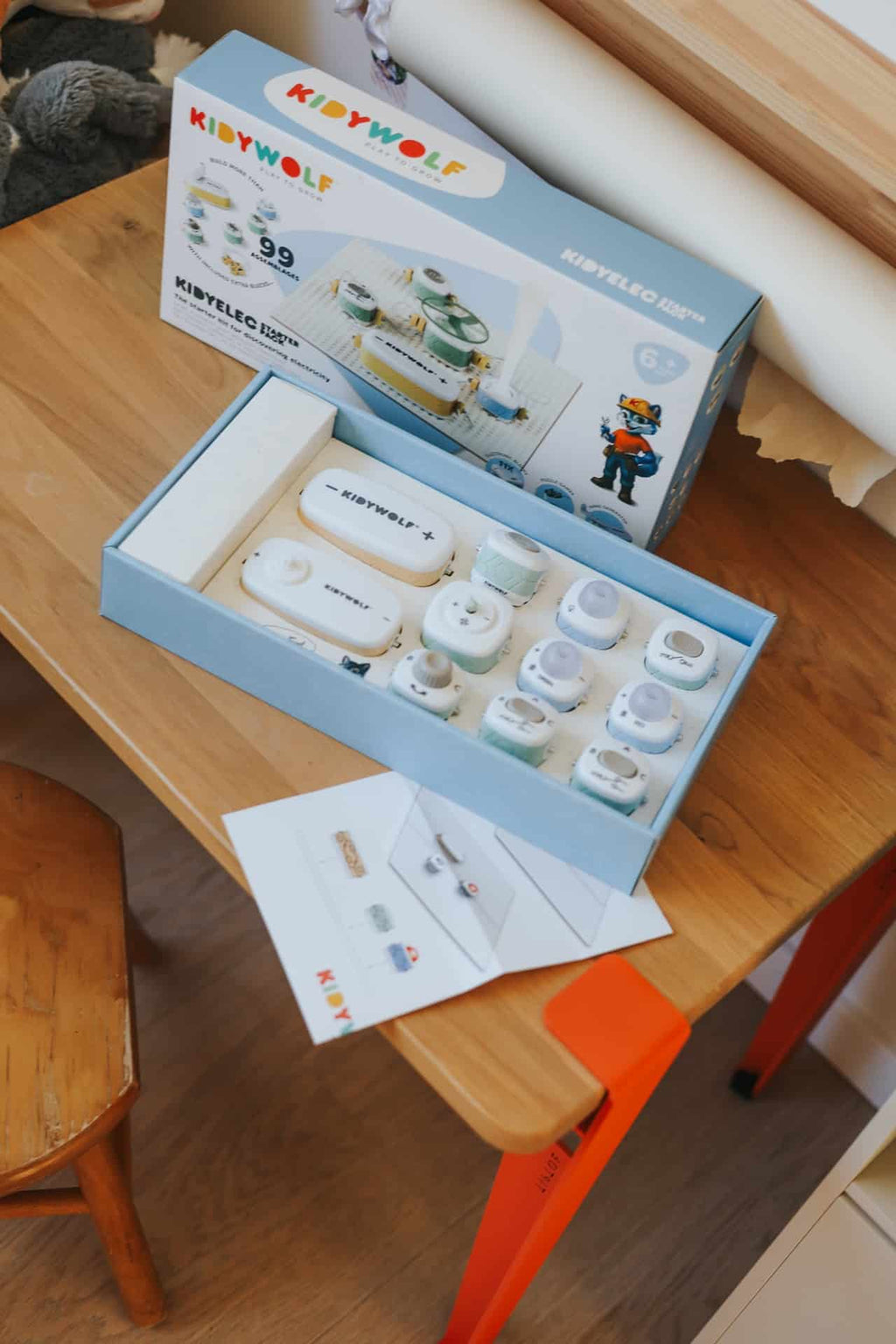 Kit KIDYELEC da KidyWolf aberto numa mesa, exibindo os componentes internos e o manual.