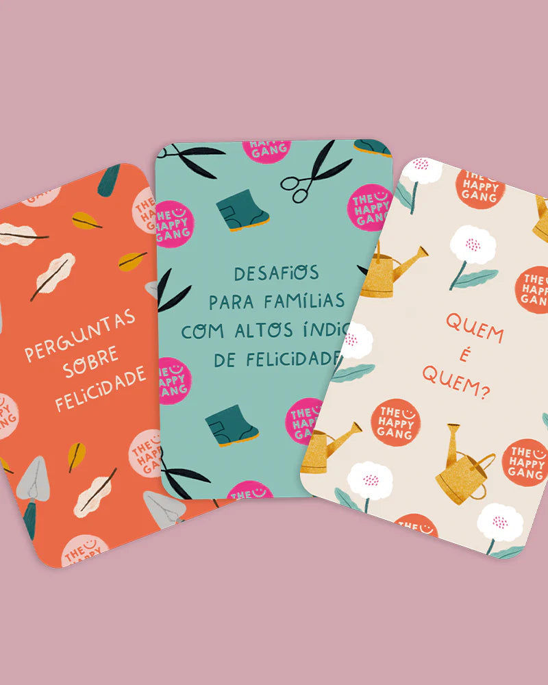 Três baralhos de cartas do kit "Famílias Felizes" com os títulos "Perguntas sobre Felicidade", "Desafios" e "Quem é Quem?".