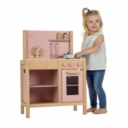 Menina pequena a brincar de pé com a cozinha de madeira Label Label Cozinha Pink.