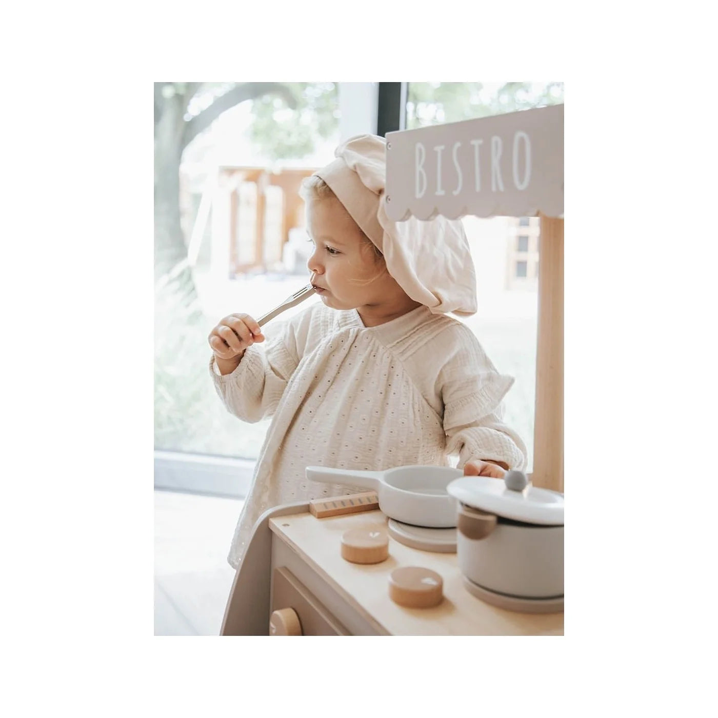 Criança pequena com chapéu de cozinheiro a brincar com os acessórios na Label Label Cozinha/Bistrô em bege.