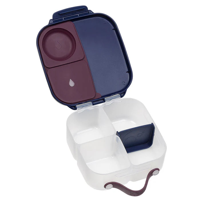 Lancheira b.box aberta, mostrando o interior com divisórias removíveis, um compartimento de silicone roxo na tampa e um separador azul escuro.
