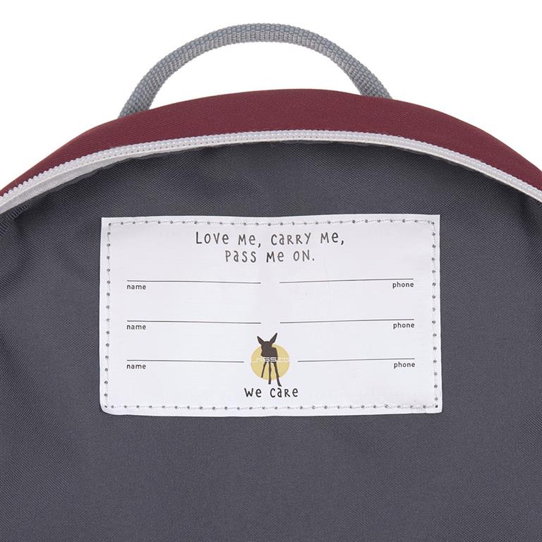 Detalhe da etiqueta interior da mochila Lassig com campos para nome e telefone, e a frase "Love Me, carry Me, Pass Me On".