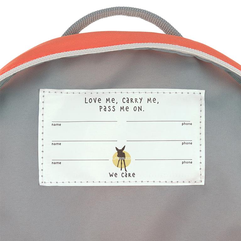 Detalhe do interior da mochila, mostrando a etiqueta com o slogan "Love Me, Carry Me, Pass Me On" e espaço para preenchimento de nome e contacto.