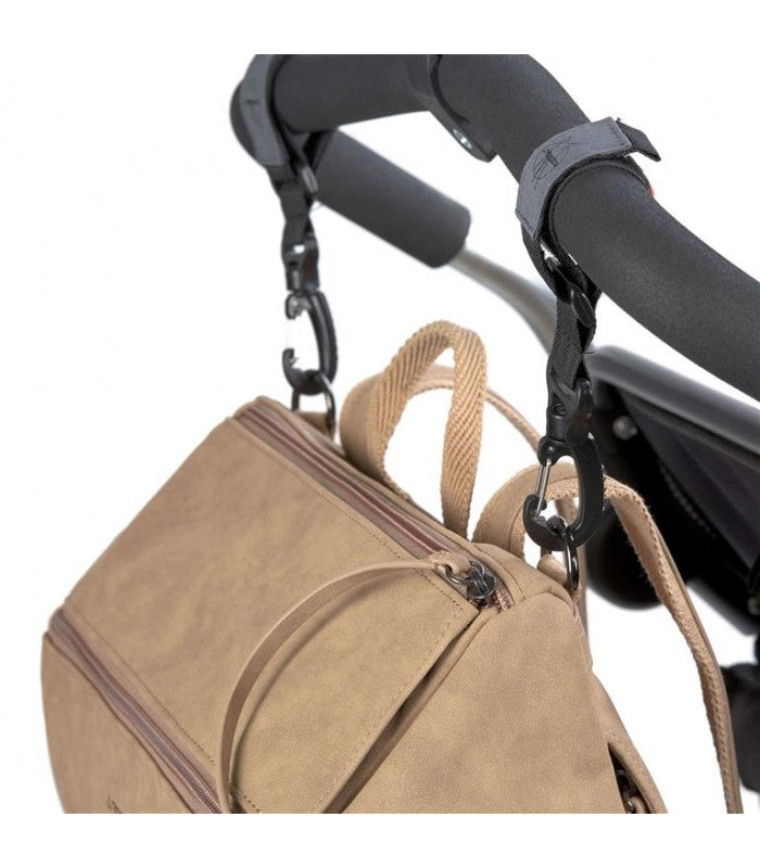 Detalhe da mochila Lassig presa ao carrinho de bebé através de ganchos pretos de engate rápido nas alças.