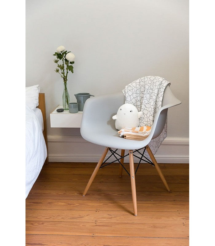 Musselinas Lassig dobradas sobre uma cadeira de design num quarto de criança com decoração minimalista e piso de madeira.