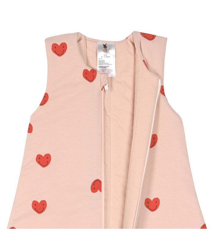 Close-up da abertura do fecho e da etiqueta de cuidados do saco de dormir com pernas Lassig rosa com corações sorridentes.