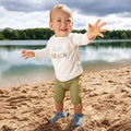 Bebé na areia com sandálias barefoot Lässig em azul escuro, desfrutando de conforto e proteção.