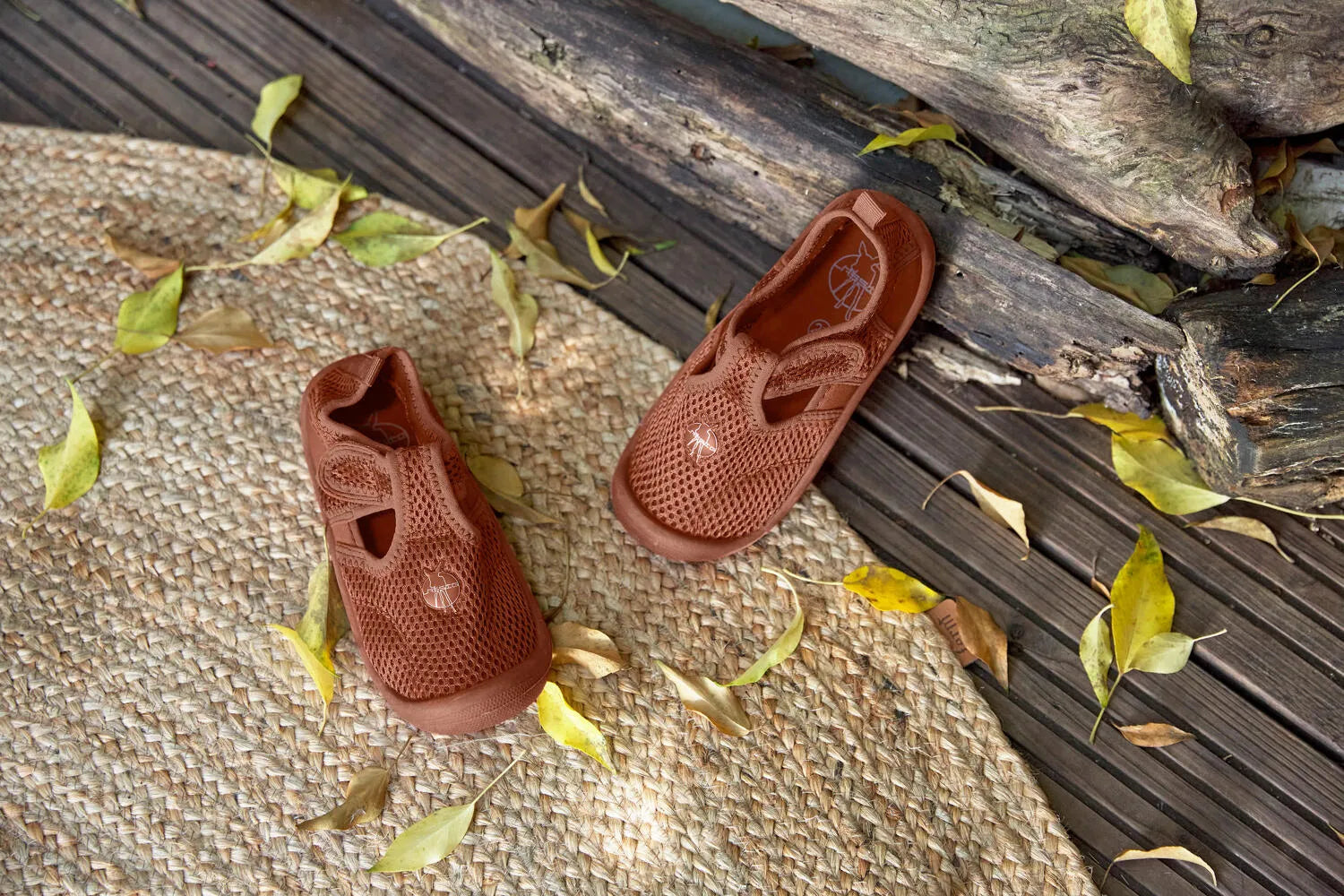  Sandálias barefoot Lässig em rust colocadas sobre folhas, destacando o design leve e o material respirável.