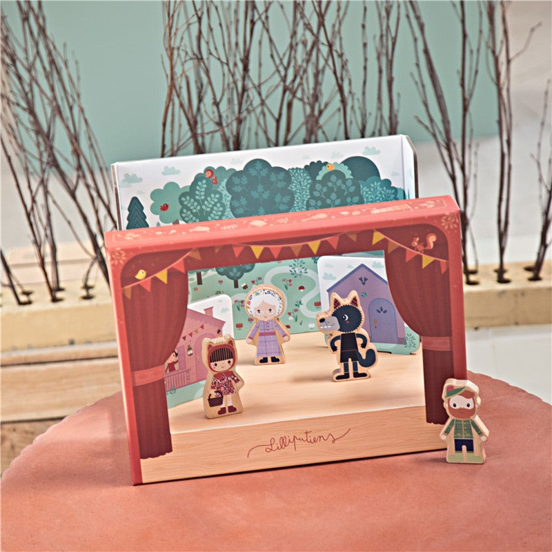 Teatro Lilliputiens montado com cenário exterior (floresta/casas) e 4 personagens em palco, com o caçador em destaque ao lado.