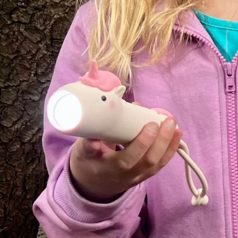 Criança a segurar a Lanterna silicone Pinky da Rabbit & Friends, mostrando o tamanho adequado para mãos pequenas e a luz brilhante.