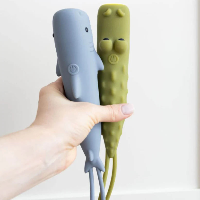 Mão a segurar a lanterna Rabbit & Friends Croco verde e uma lanterna tubarão azul em silicone.