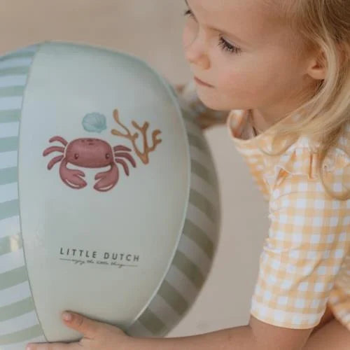 Close-up da criança a olhar para o design de caranguejo e riscas da bola de praia Little Dutch.