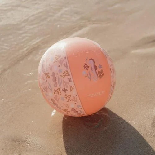 Bola de Praia Little Dutch cor-de-rosa com padrão marinho pousada na areia molhada junto à água.