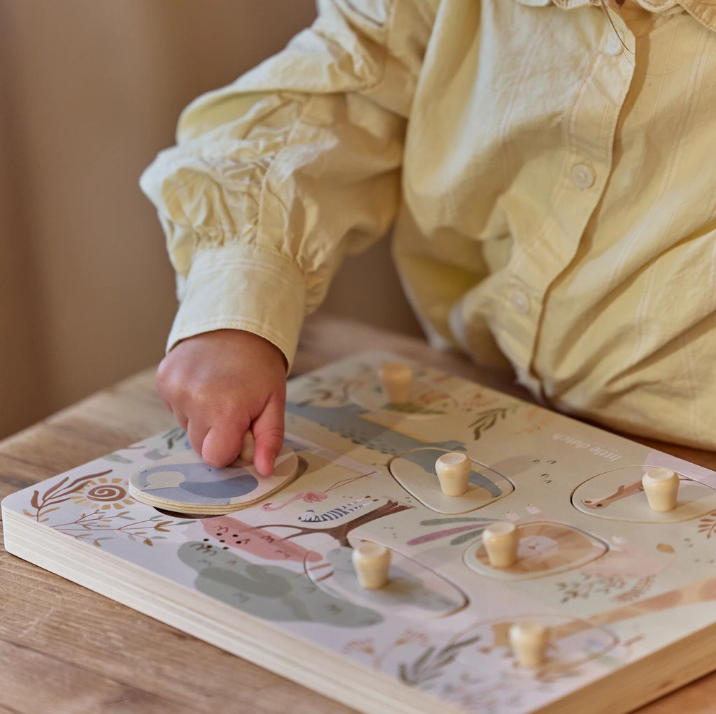 Criança a levantar uma peça do puzzle de sons Little Dutch