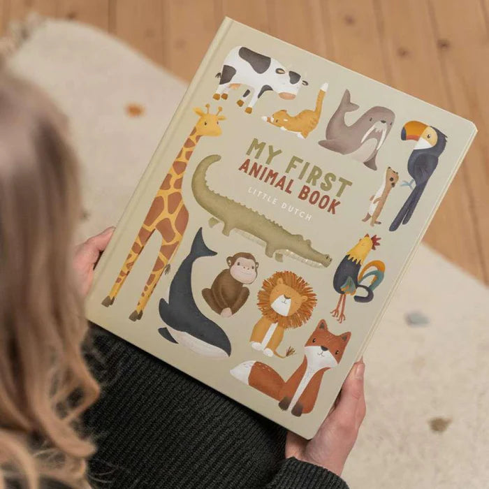 Mãos a segurarem o Livro em Inglês "My First Animal Book" da Little Dutch, mostrando a capa com a variedade de animais ilustrados.