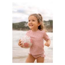 Criança sorridente na praia a segurar a Mini Bola de Praia Little Dutch com padrão floral rosa.