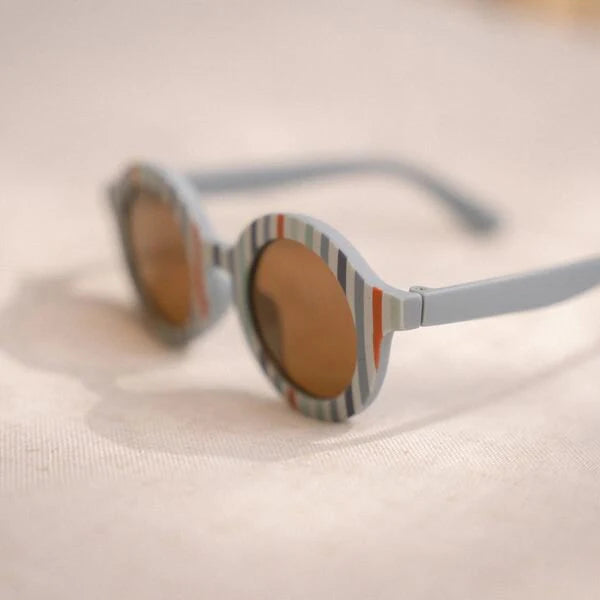 Detalhe da armação dos óculos de sol infantis Little Dutch, mostrando a textura em policarbonato azul suave com riscas multicoloridas.