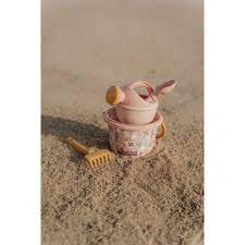 Detalhe do conjunto de praia Little Dutch rosa pousado em areia fina, mostrando o balde e o ancinho em primeiro plano.