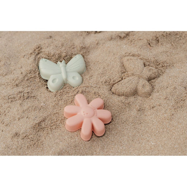 Criança a brincar com o conjunto de praia Little Dutch, usando a pá para encher um balde (não incluído) na areia.