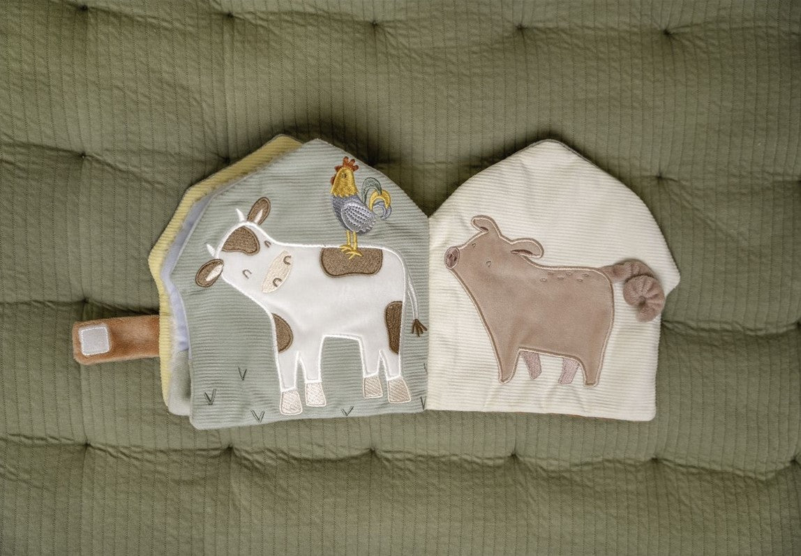 Duas páginas abertas de um livro de atividades de tecido, mostrando uma vaca com um galo em cima e um porco, com texturas e bordados detalhados.