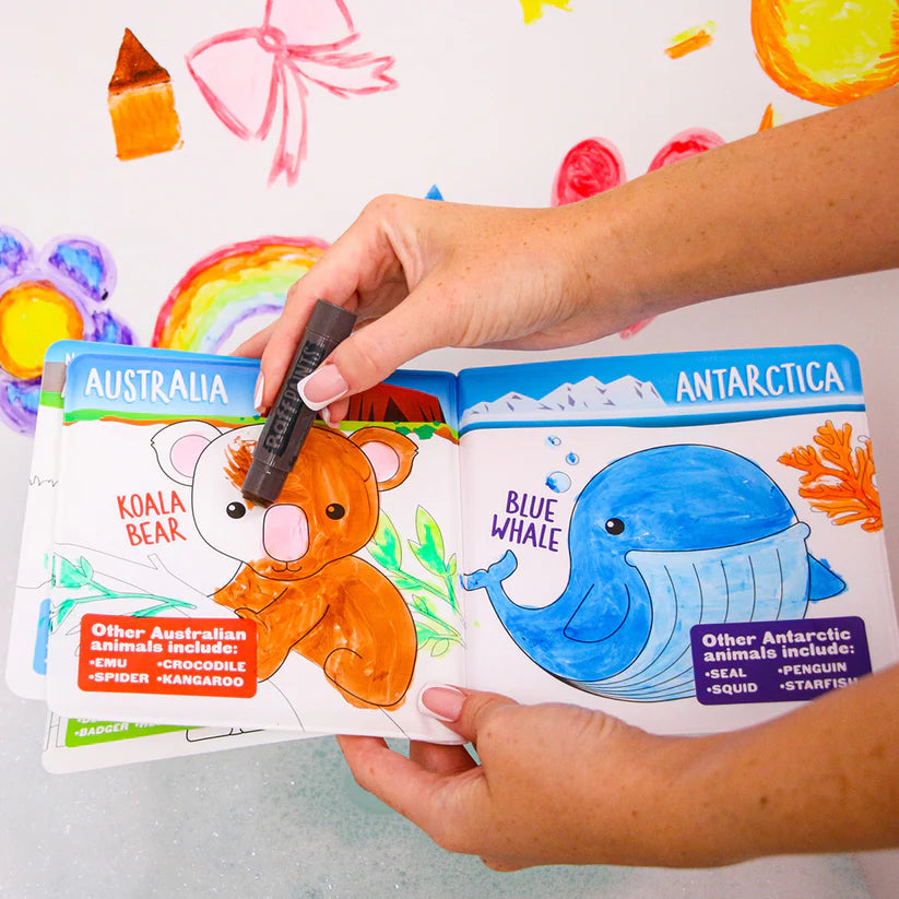 Mãos a colorir o livro de banho temático "Animais pelo Mundo", focando nas páginas da Austrália (Coala) e Antártida (Baleia Azul).