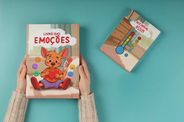 Duas mãos seguram um livro infantil intitulado 'Livro das Emoções', com um canguru ilustrado a segurar um coração e botões coloridos representando diferentes emoções e sentimentos. Ao lado, um segundo livro chamado 'Hoje Sinto-me Assim' exibe um termómetro de emoções colorido sobre um fundo azul. Ambos os livros são voltados para crianças e abordam emoções básicas de forma interativa.