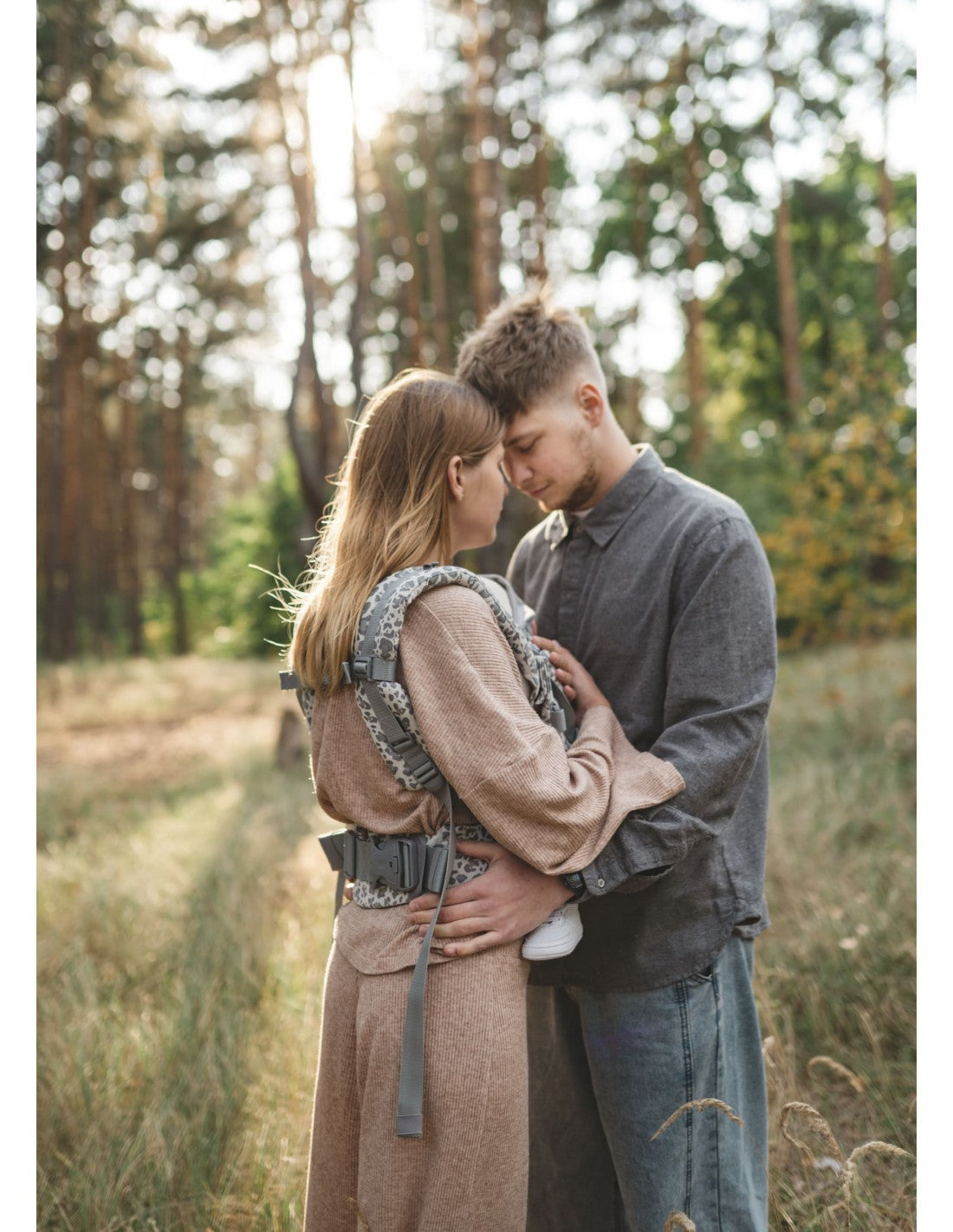 Dois adultos a conversar enquanto uma mulher usa a mochila Love and Carry ONE - Leo.