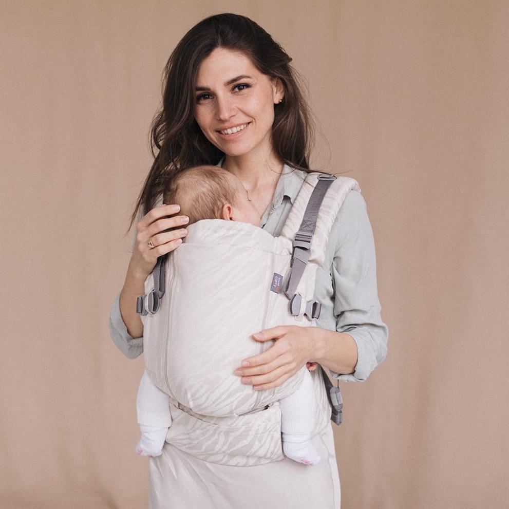 Mulher sorridente usando a mochila Love and Carry ONE com bebé.