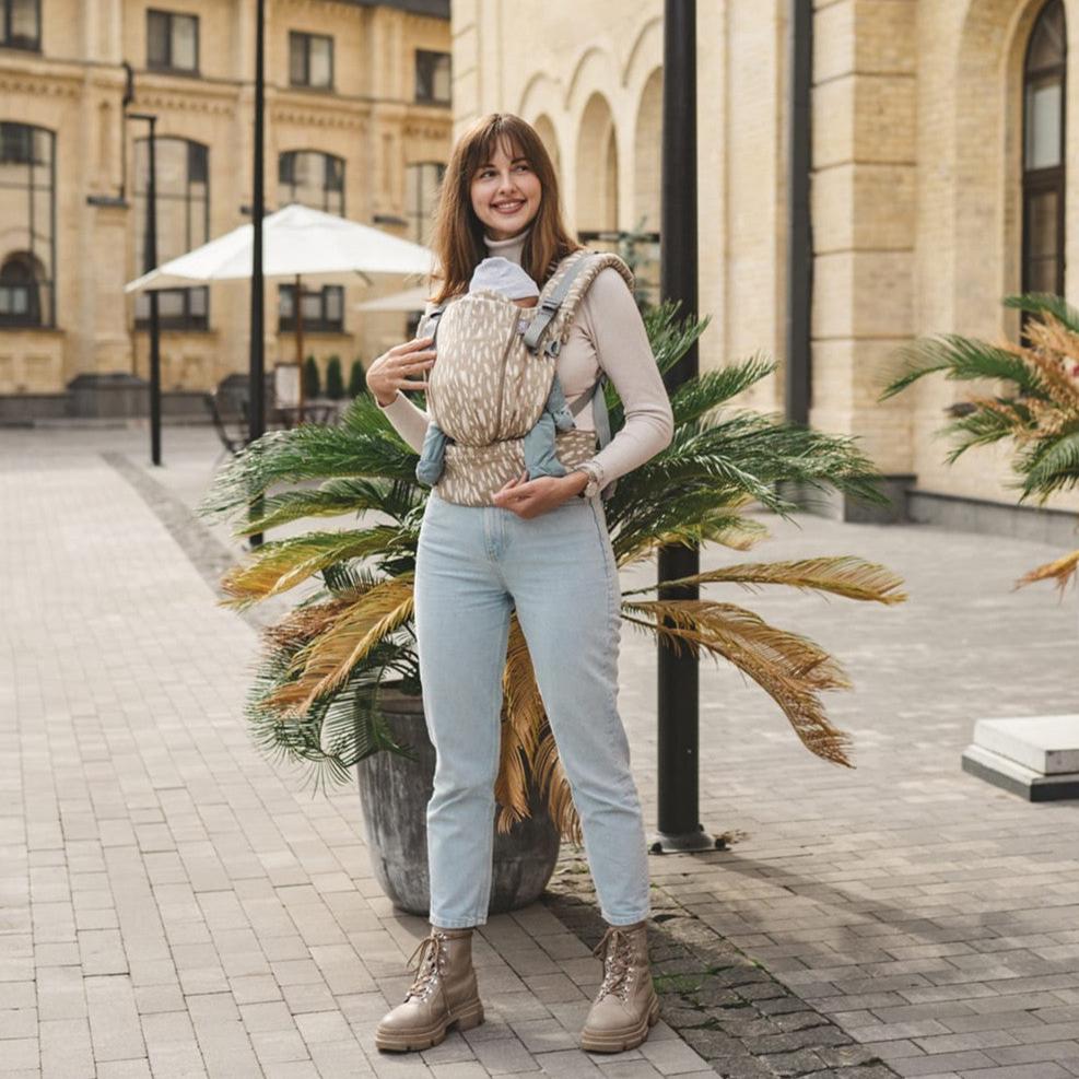 Mulher a usar a mochila Love & Carry ONE - Sand, com fundo de cidade.