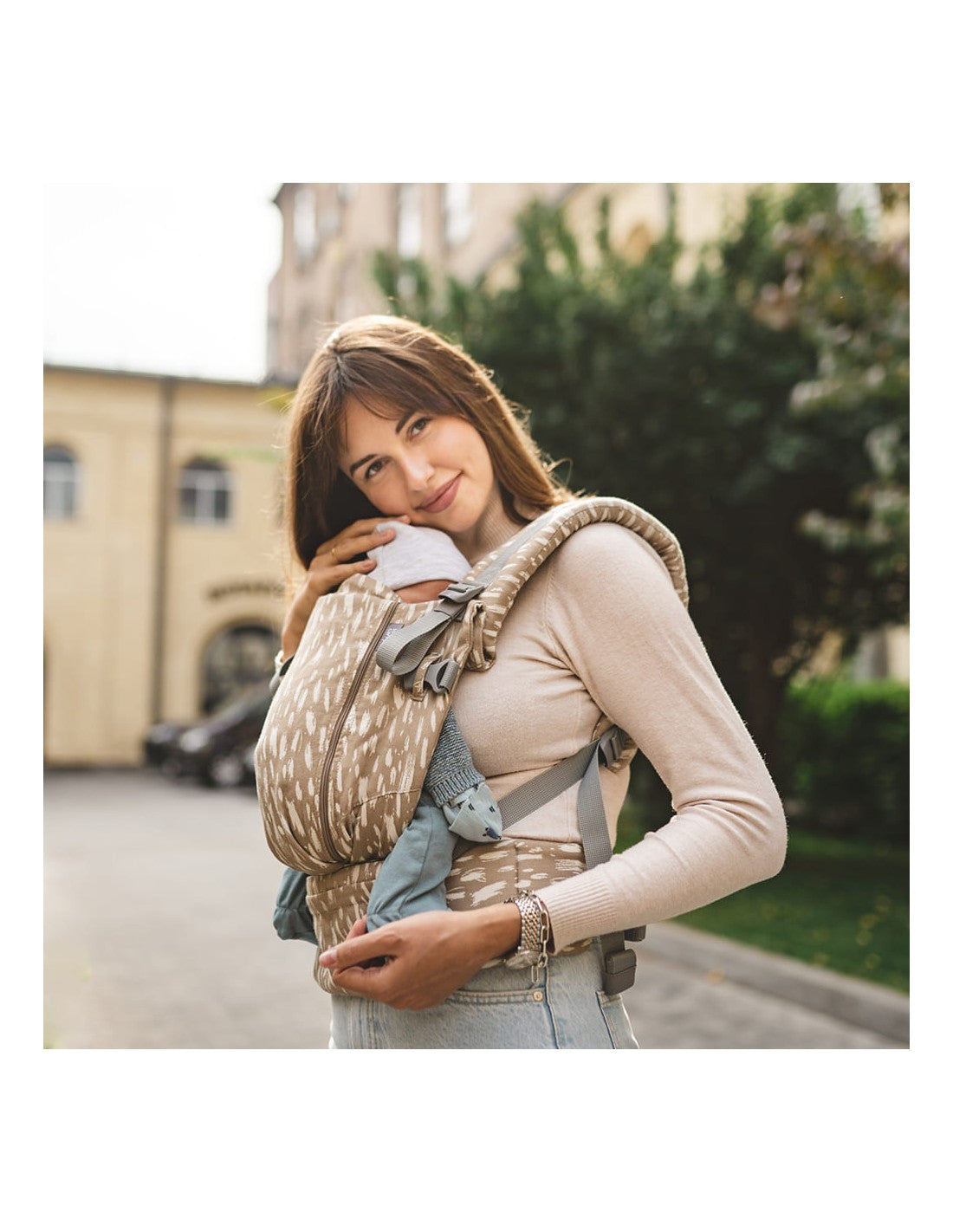 Mulher a usar a mochila Love & Carry ONE - Sand, com fundo de cidade.