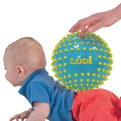 Detalhe de uma bola sensorial Ludi com nervuras grossas e textura suave, mostrada na mão de um bebé.