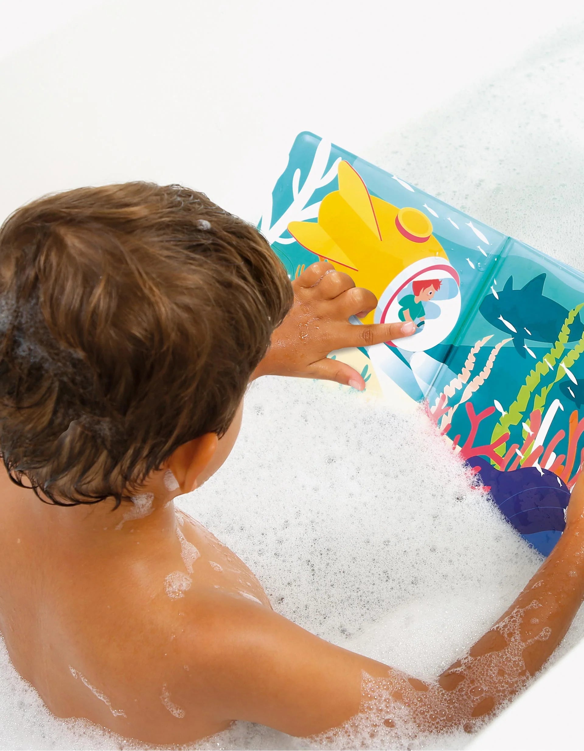 Criança a brincar na banheira com espuma, a interagir com o Livro de Banho Mágico Ludi, mostrando um submarino amarelo e vida marinha.