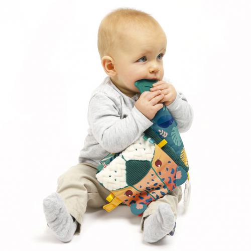 Bebé sentado a explorar e a morder o Livro sensorial Selva Ludi, que apresenta texturas e cores da selva.