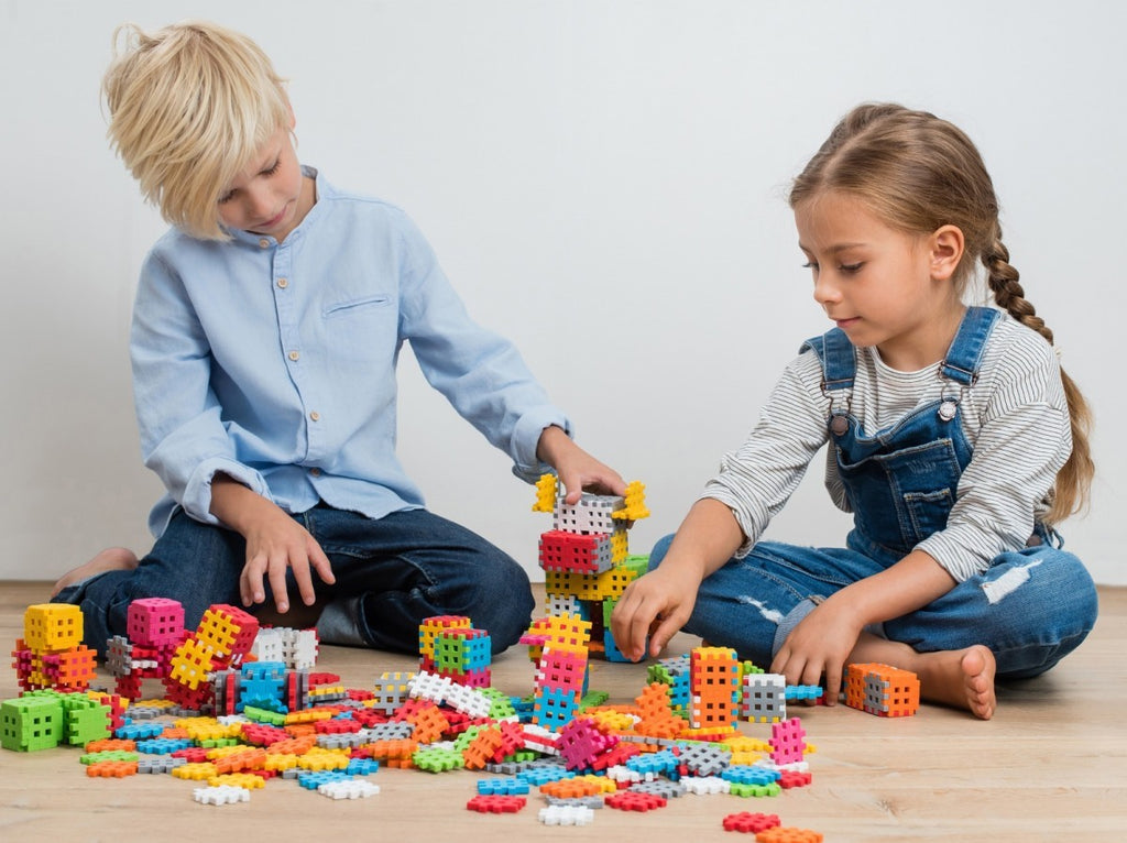 Crianças a brincar com os blocos de construção Mini Waffle Marioinex, construindo estruturas criativas. Cores vibrantes e diversão garantida!