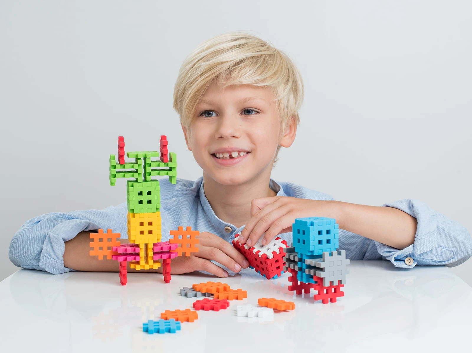 Criança sorridente a brincar com os blocos Mini Waffle Savana da Marioinex, construindo torres e figuras coloridas.