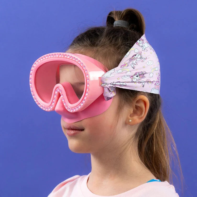 Menina com óculos Waterplops cor-de-rosa com diamantes, e banda de unicórnios e arco-íris, vista lateral.