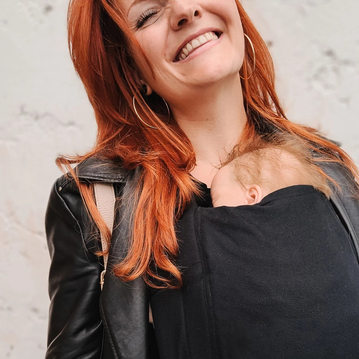 Bebé pequeno transportado na posição frontal com o Mei Tai Hoppediz Bondolino B.Pure All Black, posição ergonómica "M".