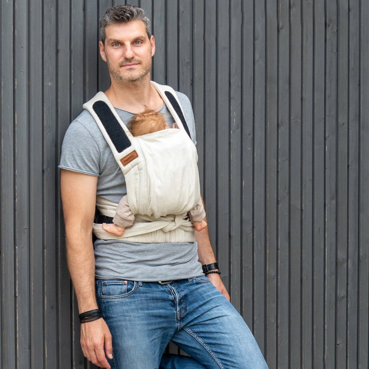 Bebé seguro na posição ergonómica "M" (joelho a joelho) no porta-bebés Mei Tai Hoppediz Bondolino B.Pure Cádiz, apoiado nas costas do cuidador.