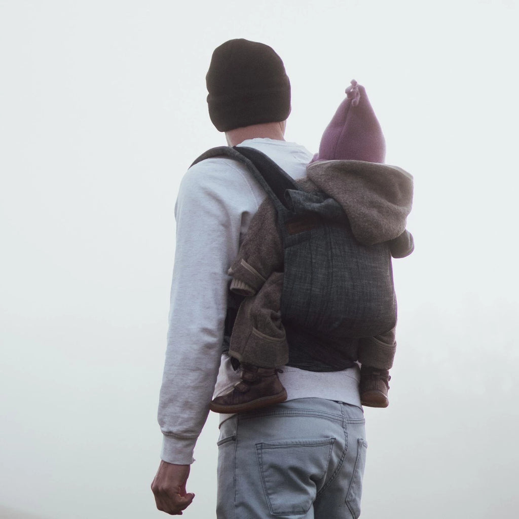 Bebé transportado na posição frontal com o Mei Tai Hoppediz Bondolino, demonstrando a posição ergonómica em "M" (joelho a joelho).