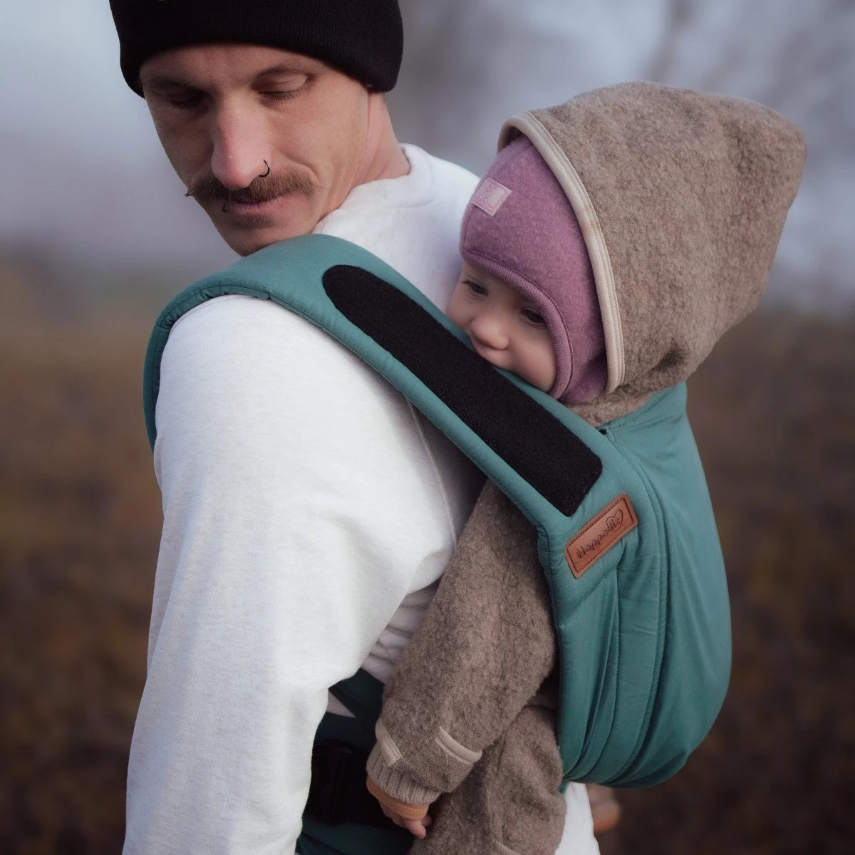 Close-up da secção do assento do porta-bebés, ilustrando a posição ergonómica em "M" que suporta o bebé do joelho ao joelho.
