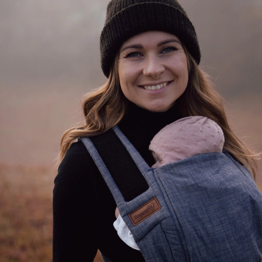 Bebé transportado na posição frontal com o Mei Tai Hoppediz Bondolino B.Pure Denim, demonstrando o suporte ergonómico em "M" joelho a joelho.
