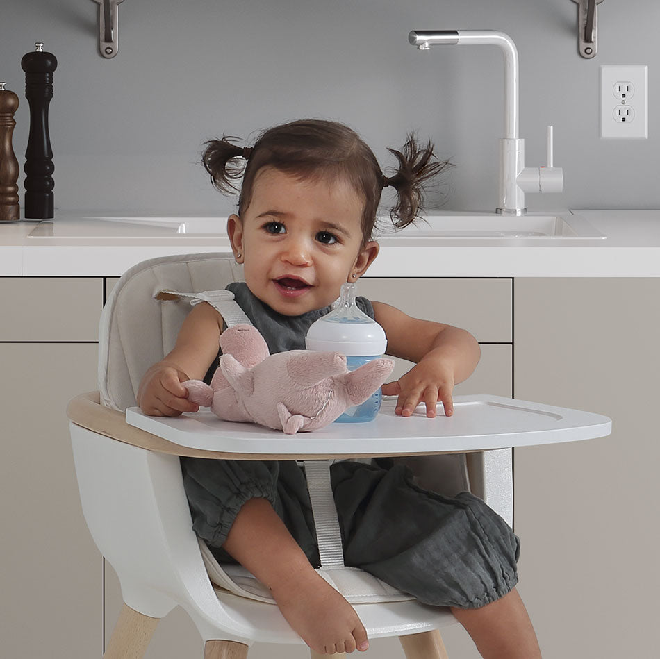 Bebé sorridente a usar a cadeira de refeição Micuna OVO com almofada bege e tabuleiro, pronto para a refeição.