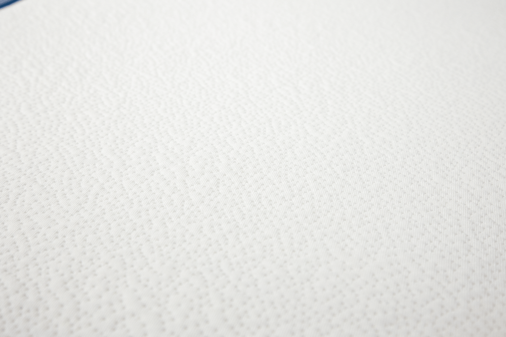 Detalhe da textura suave e acolchoada do tecido 100% poliéster do colchão Micuna para berço.