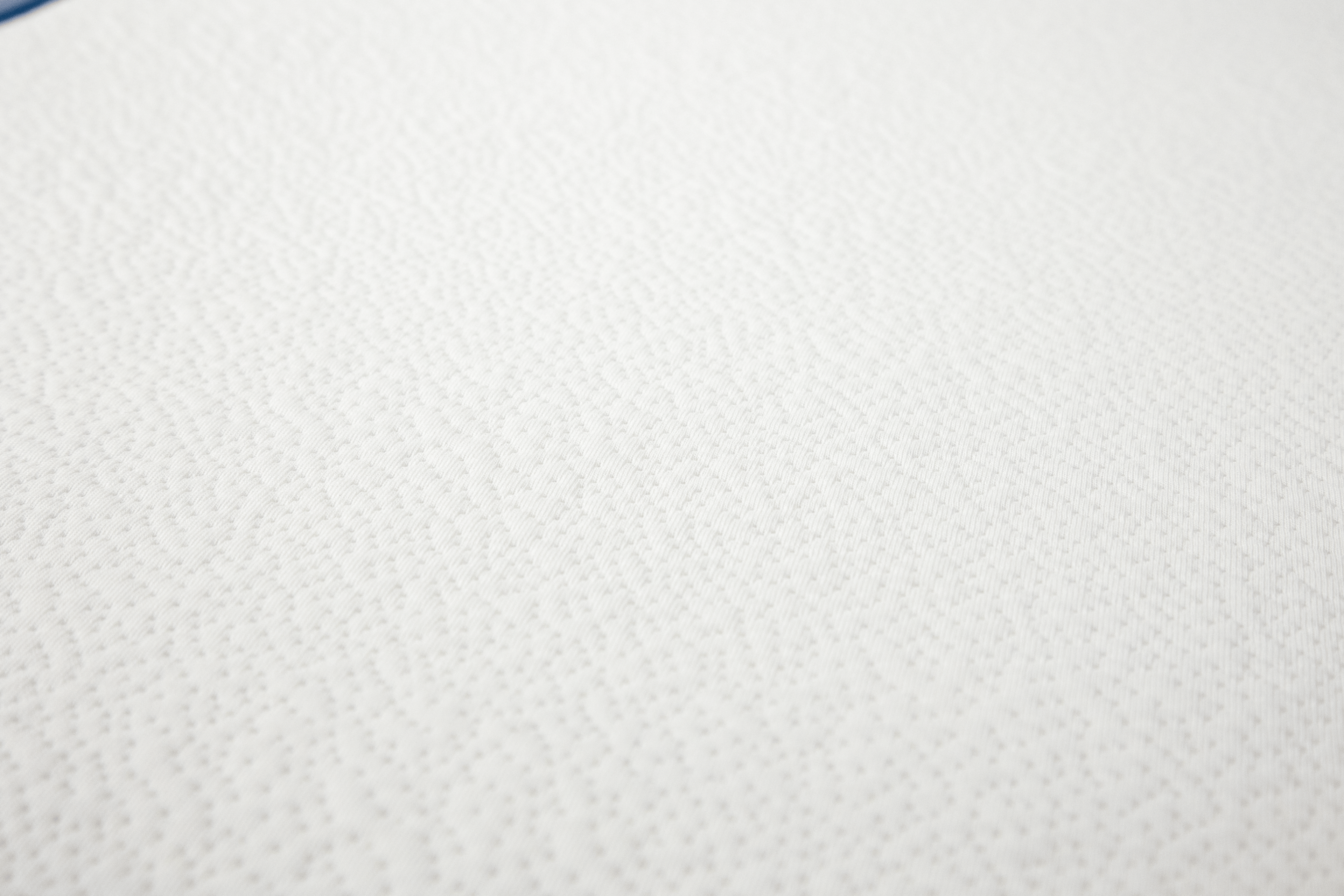 Detalhe da textura suave e acolchoada do tecido 100% poliéster do colchão Micuna para berço.