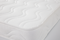 Detalhe do canto de um colchão viscoelástico Micuna branco para berço, mostrando a costura do ribete e o padrão ondulado do tecido acolchoado.